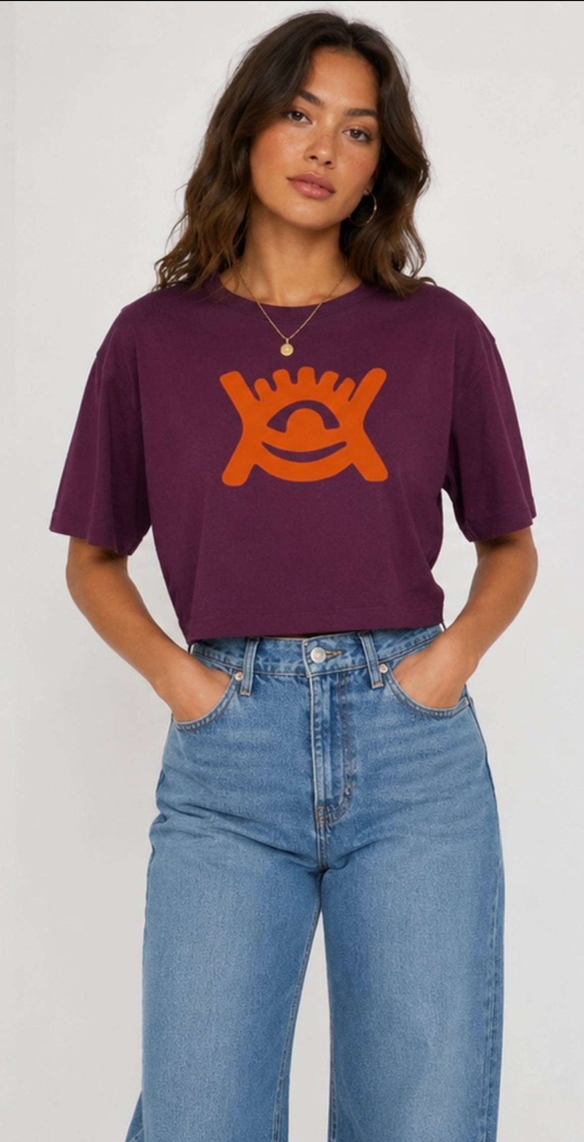 Wearing high waisted blue denim jeans and cropped mulberry coloured T-shirt with orange adinkra print. 