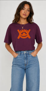 Wearing high waisted blue denim jeans and cropped mulberry coloured T-shirt with orange adinkra print. 