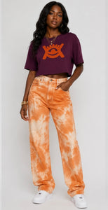 Model wearing cropped mulberry coloured top, wearing orange jeans and white trainers. 