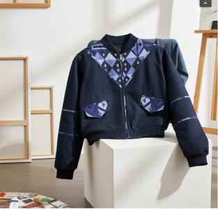Navy blue jacket with geometric pattern on a white pedestal in a minimalistic room.