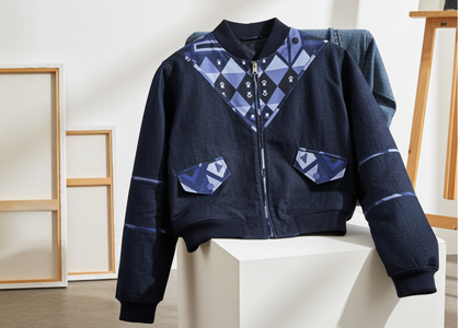 Blue jacket with geometric pattern on a white pedestal against a minimal background