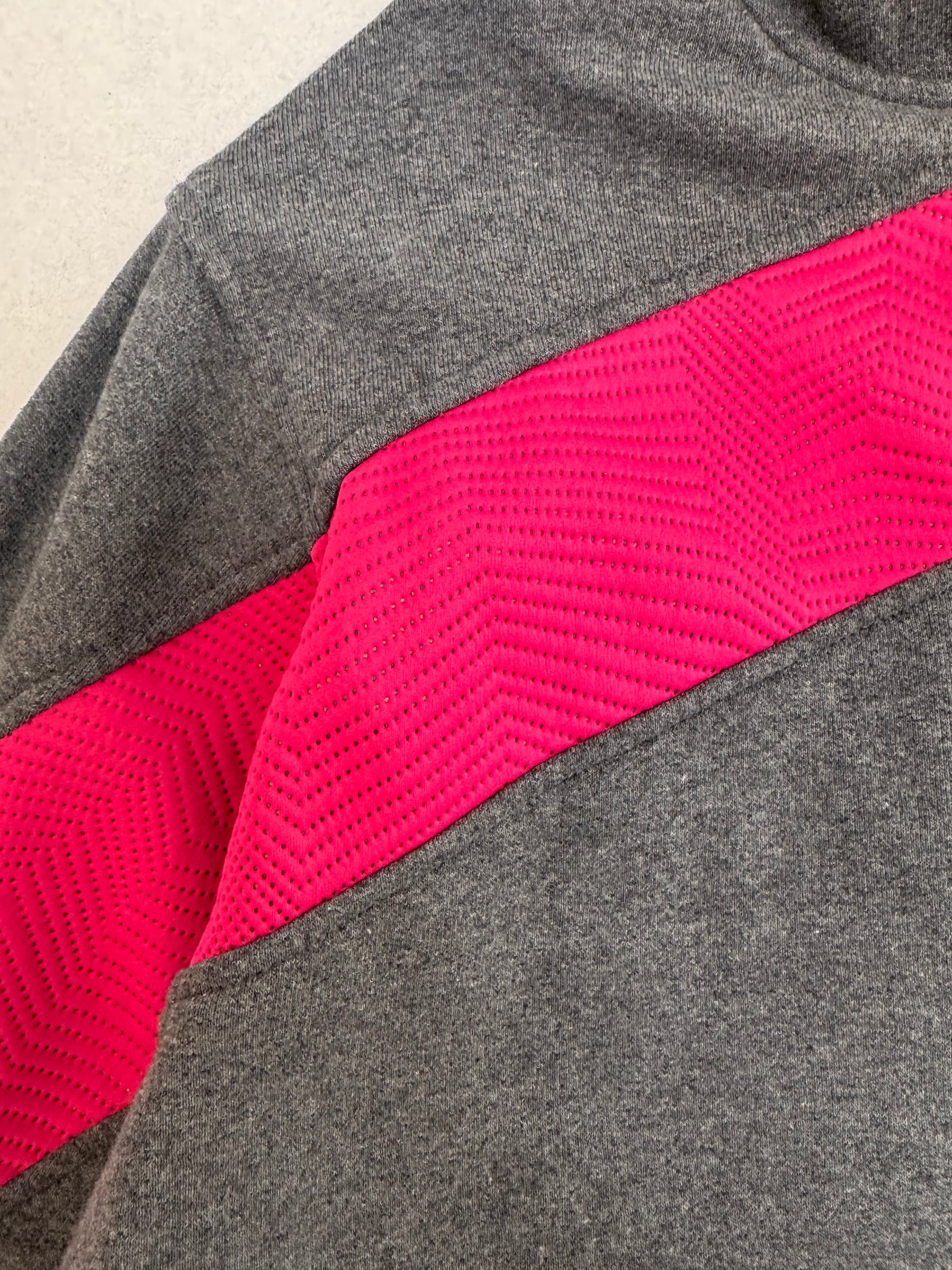 Gray and pink athletic outfit with mesh panel on a neutral background