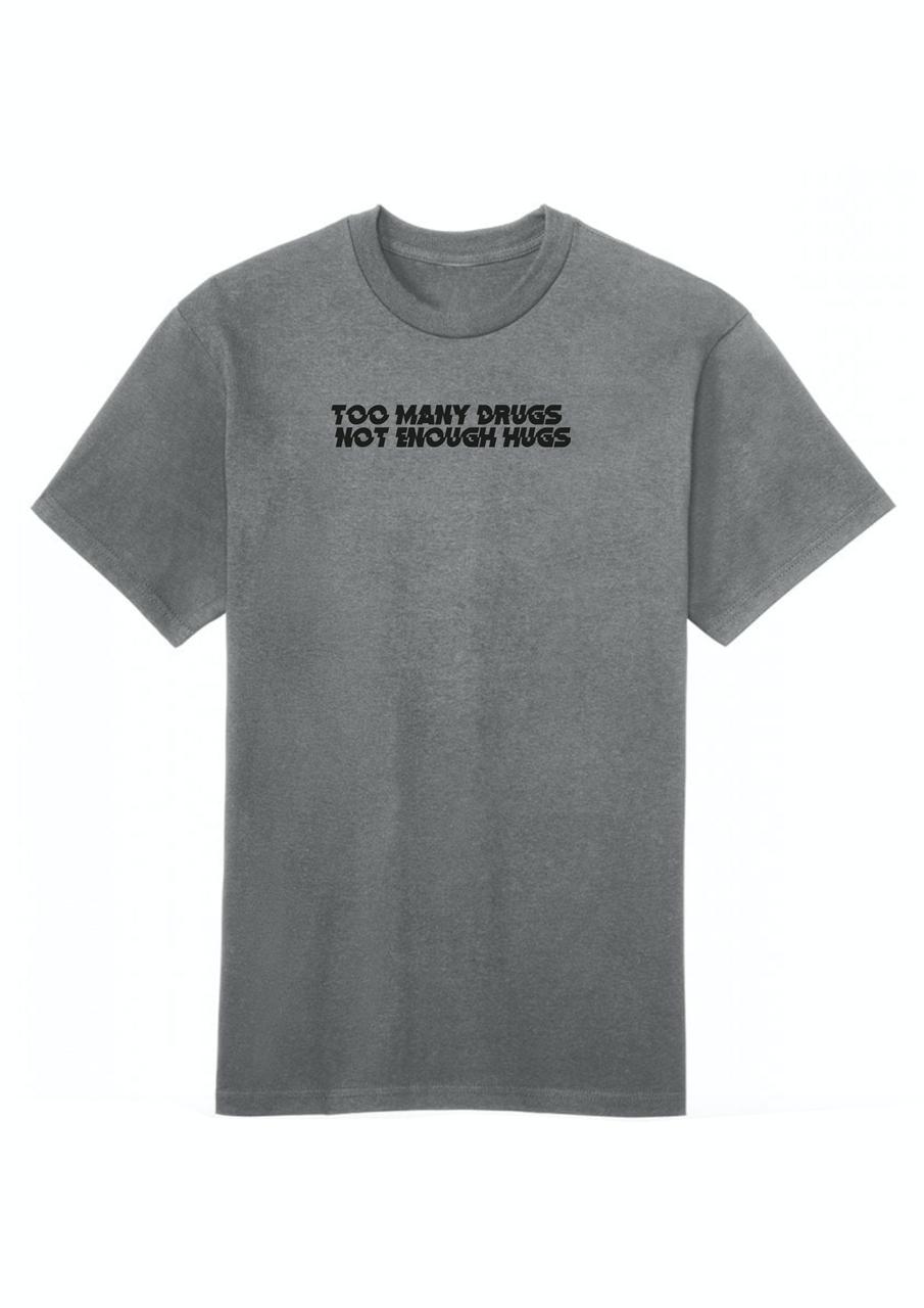 A gray cotton crew neck t-shirt with the text 'TOO MANY DRUGS NOT ENOUGH HUGS' printed on the front.