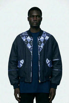 Man wearing a dark jacket with geometric patterns on a white background