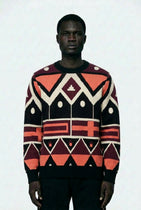 Person wearing a patterned sweater with geometric design on a white background