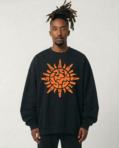 Person wearing a black sweatshirt with an orange geometric design on a plain background