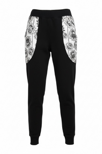 Black jogger pants with white floral patterns on a white background