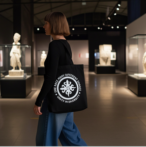 Person walking in a museum with a black tote bag featuring a white logo and text.